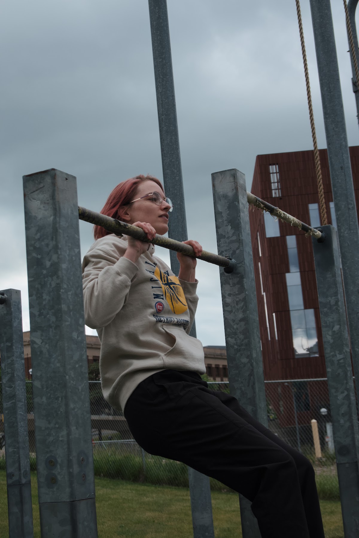 Michigan Parkour member hanging from an outdoor bar